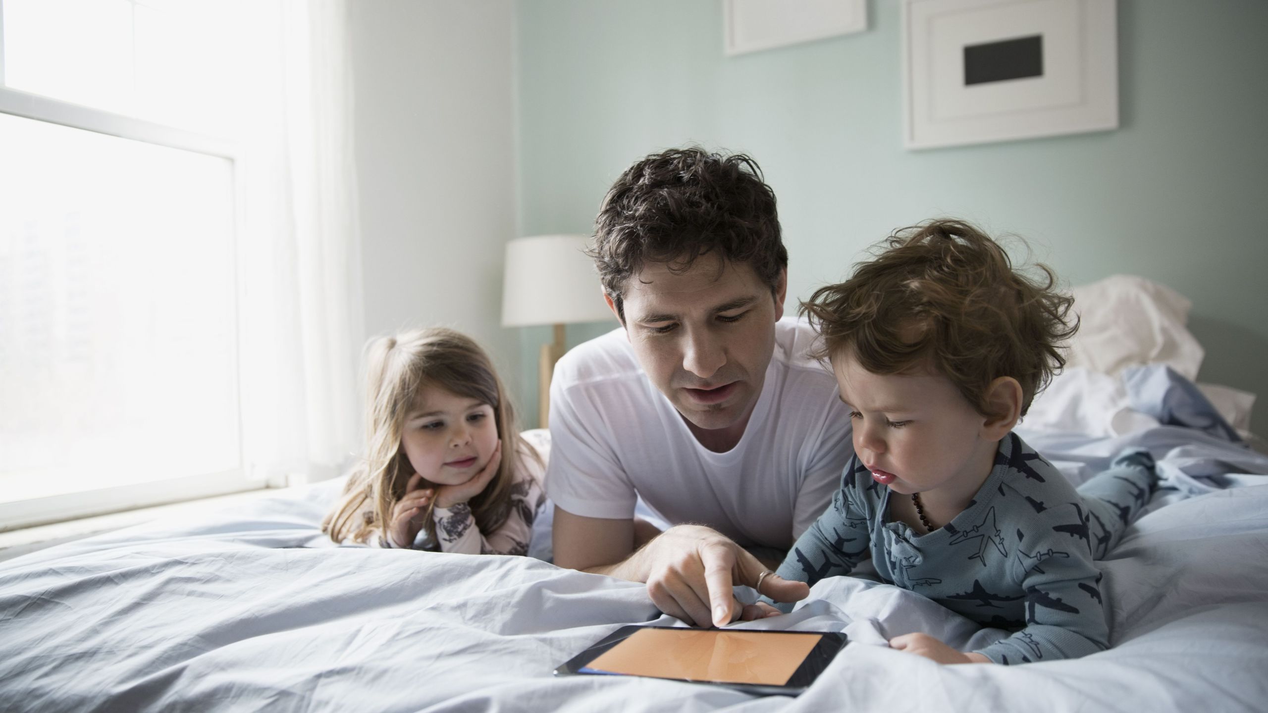 Father and children using tablet in bed 5940a46b5f9b58d58ac