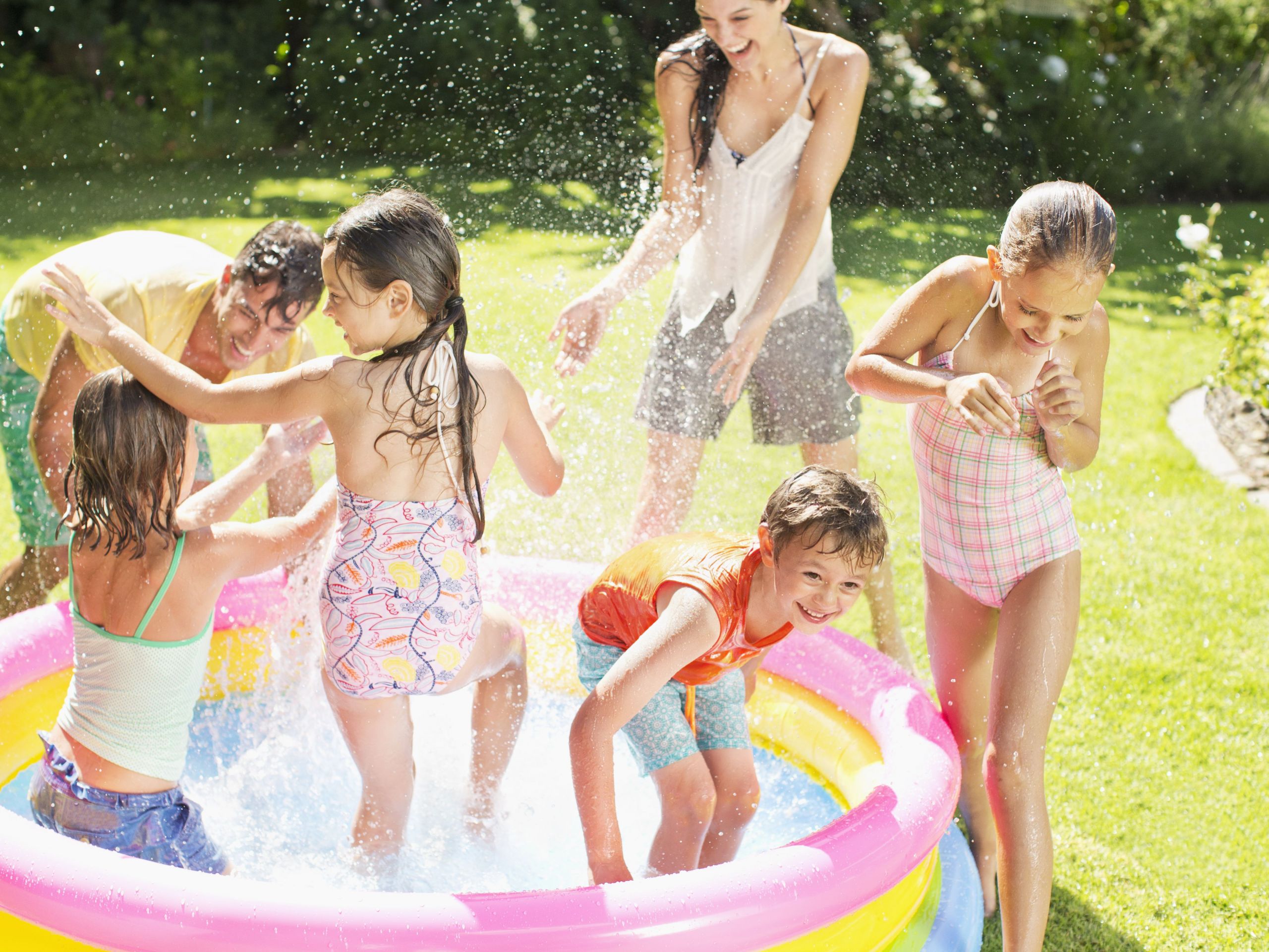 family playing in paddling pool in backyard 57d f9b589b0ab5ad7e