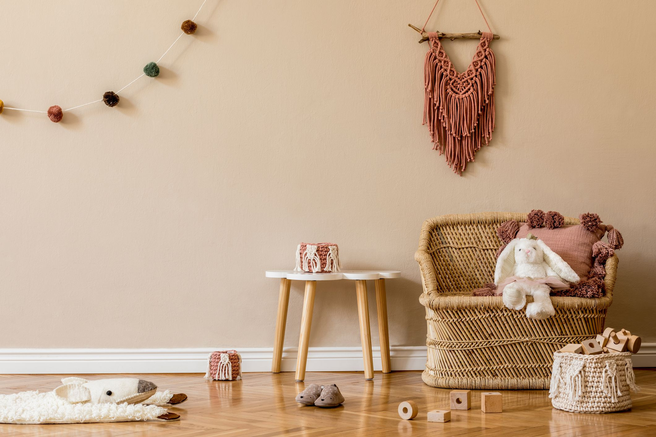 stylish and cute scandinavian decor of newborn baby room with natural toys hanging decor balls macrame pouf plush animals and teddy bears beige walls interior design of kid room home staging 9e f44ad496ca2e694b56a3065a7